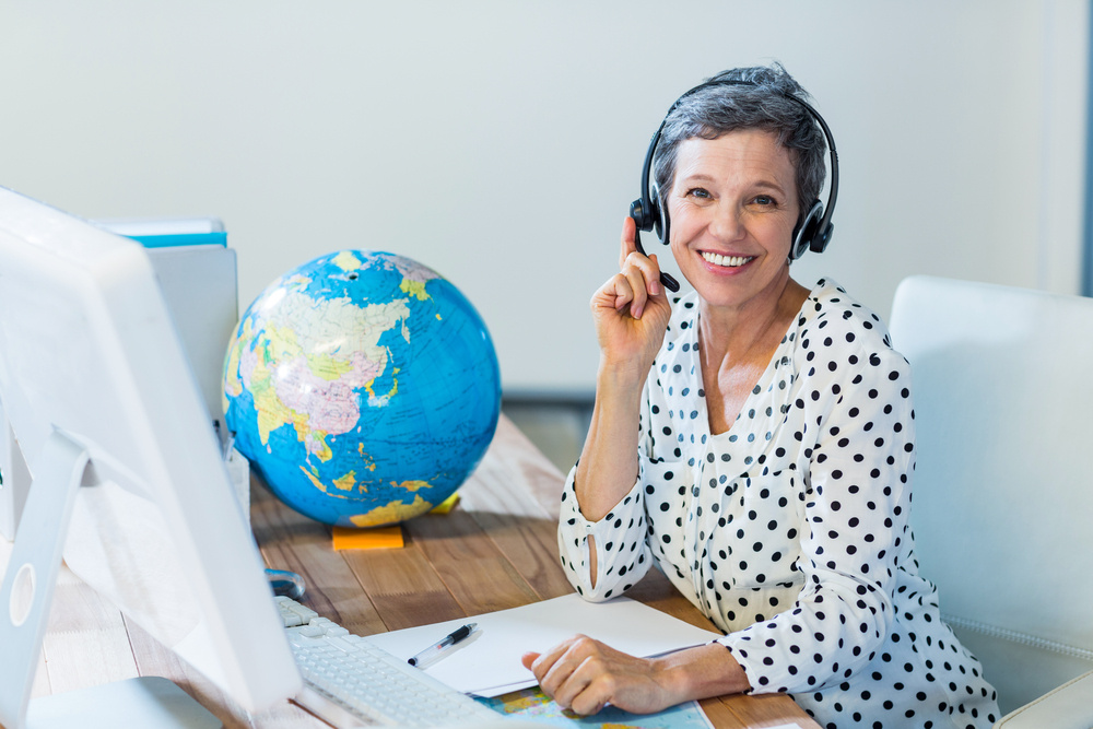 Smiling travel agent sitting at her desk in the office